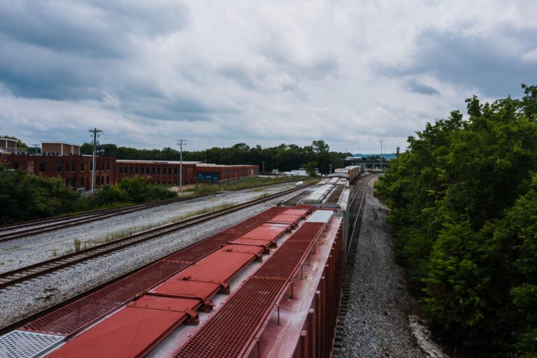 Aerial view of train tracks near an industrial complex under cloudy skies.